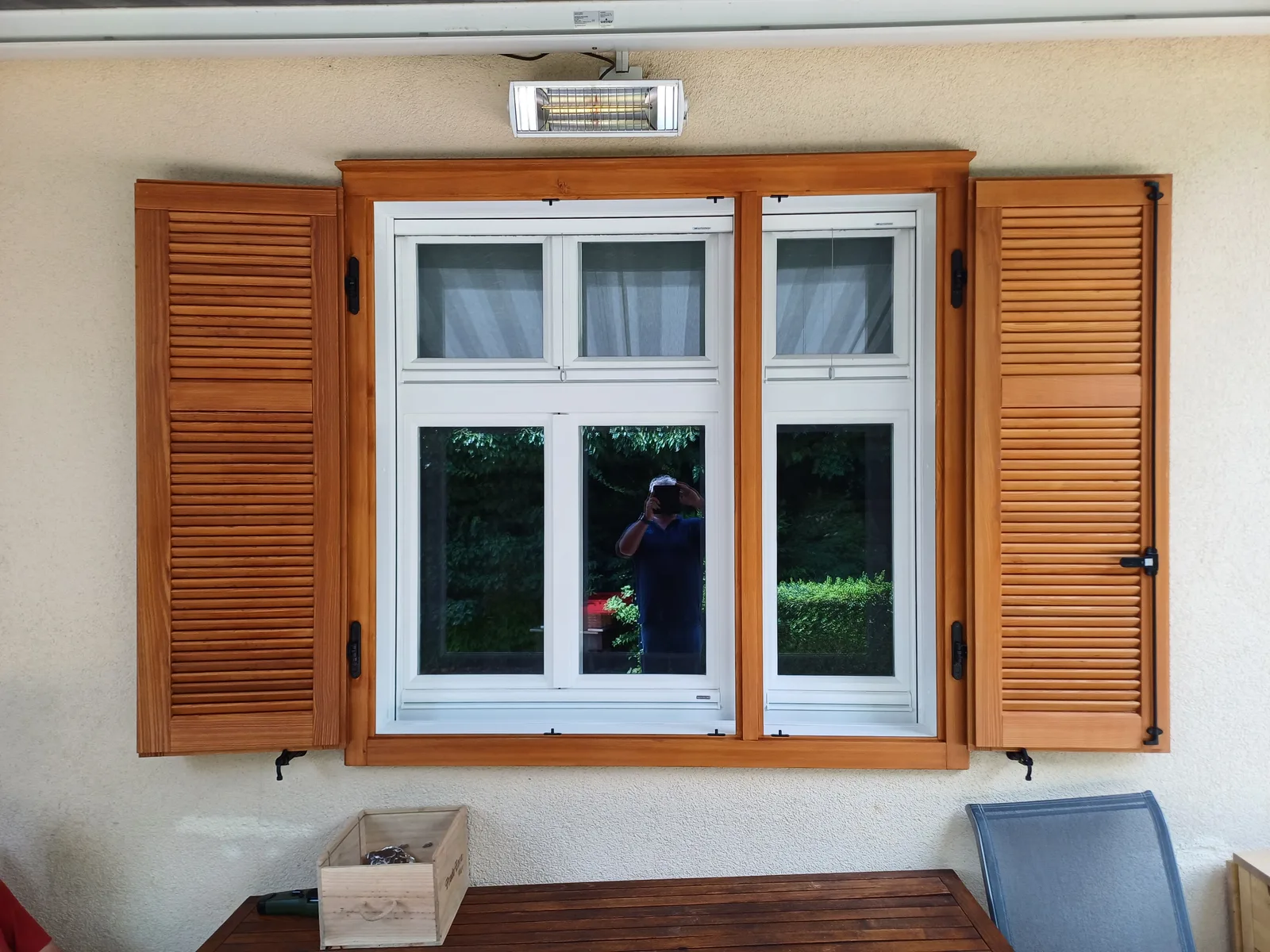 Weißes Kastenstockfenster mit Holzrahmen und geöffneten Holzläden