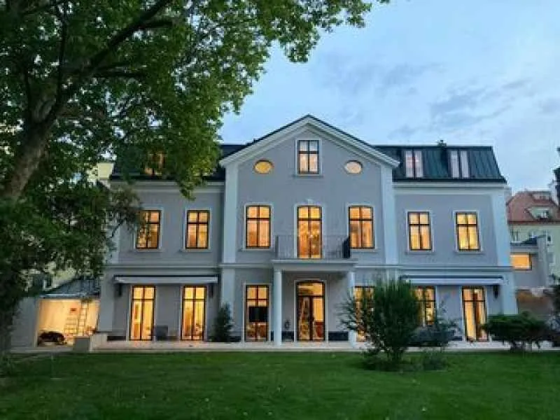Villa am Abend mit beleuchteten Sprossenfenstern
