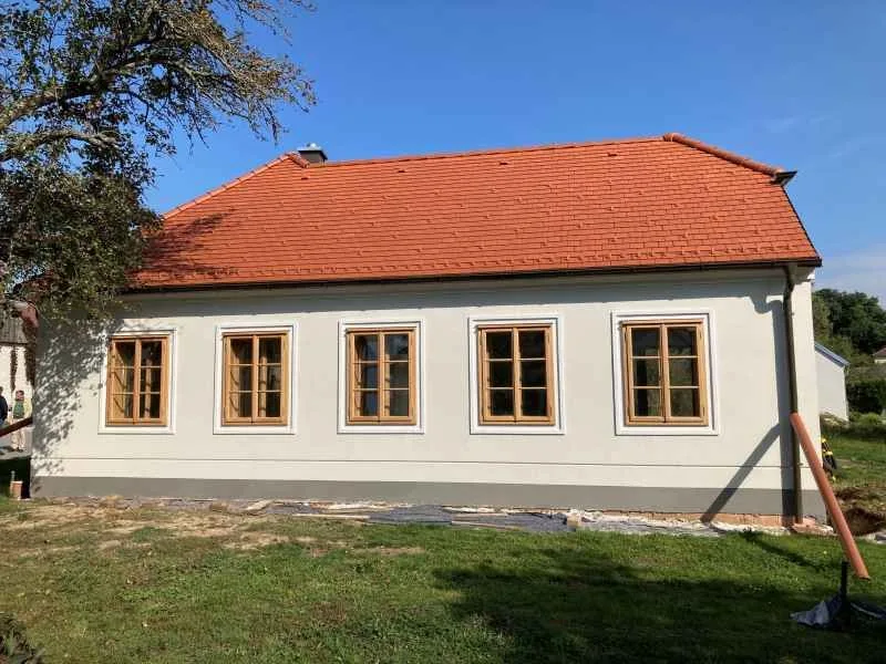 Haus mit Holzfenstern unter rotem Ziegeldach