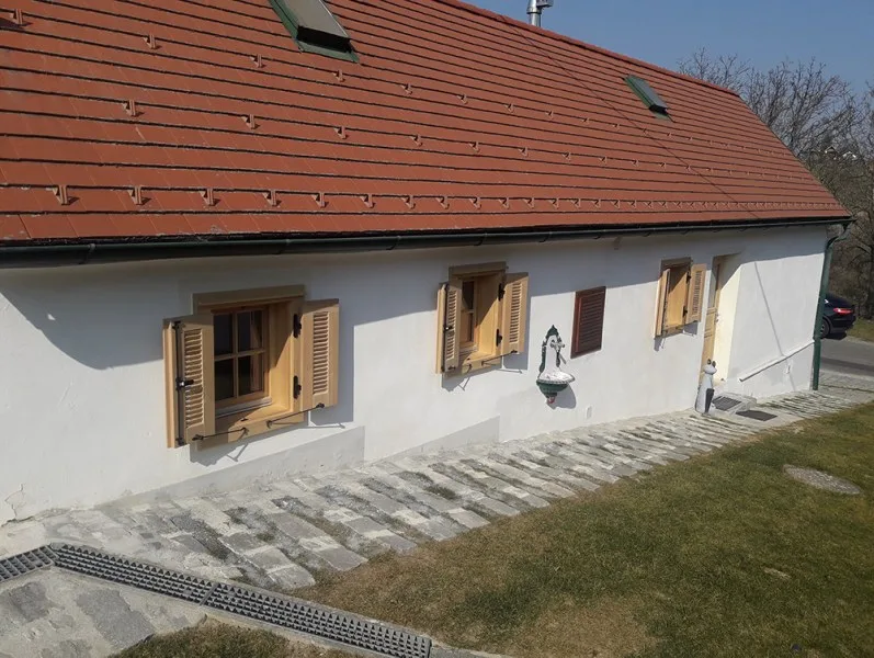 Weißes Haus mit Holzfensterläden und roten Dachziegeln