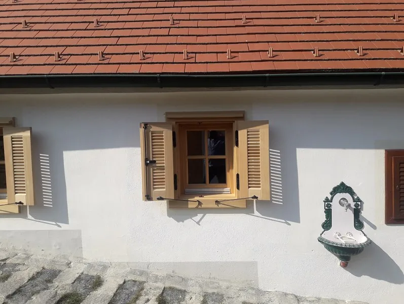 Holzfenster mit Fensterläden an weißer Fassade, Nahaufnahme