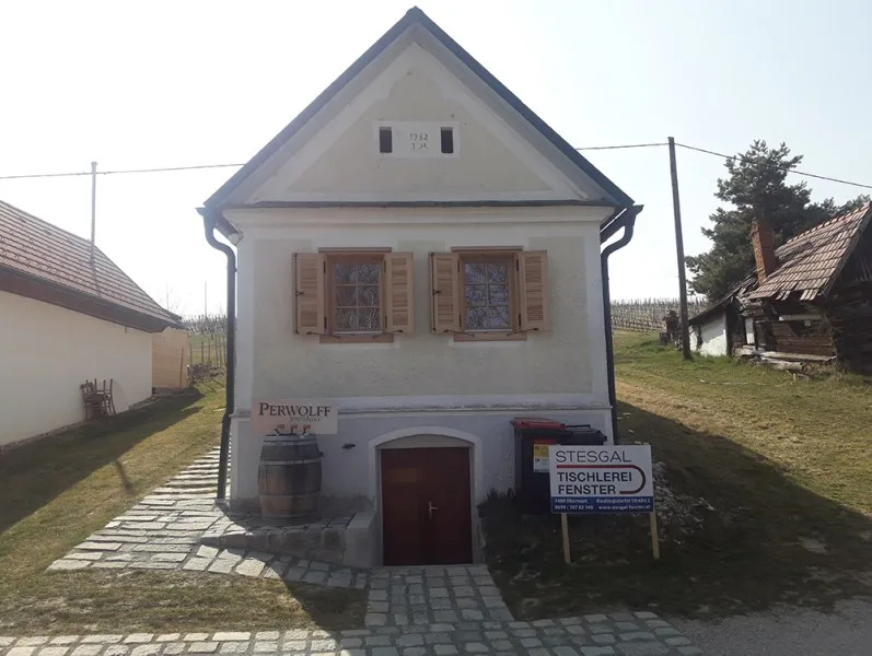 Kellerstöckl mit Holzfenstern und Fensterläden, davor eine Bautafel STESGAL Tischlerei Fenster