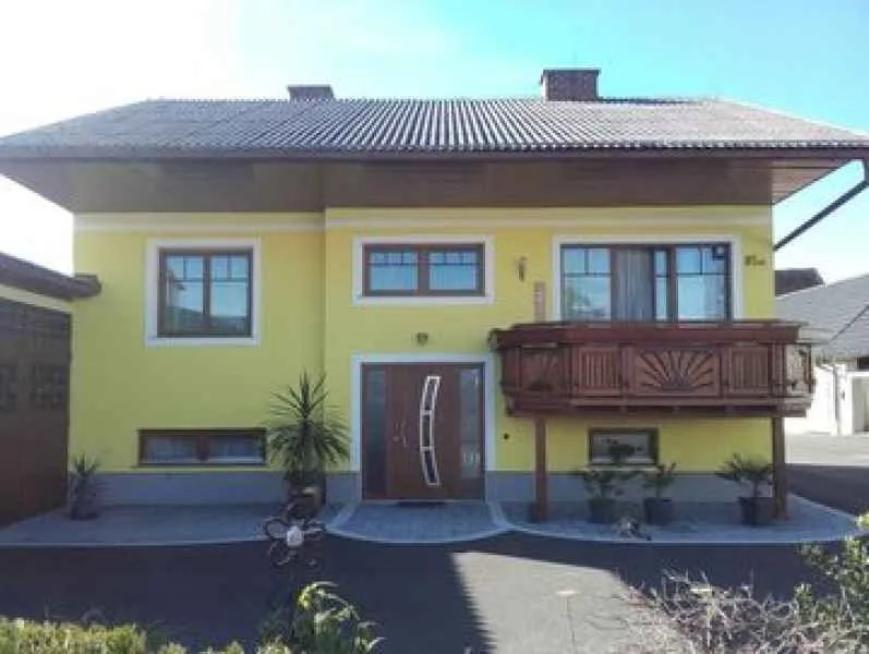 Gelbes Wohnhaus mit Eingangstür und Holzbalkon